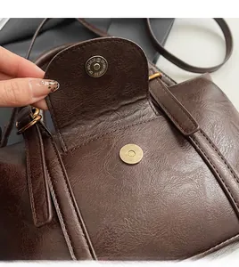 Close-up of premium dark brown leather texture with a gold magnetic clasp on handbag