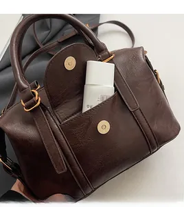 Detailed macro view of retro brown pillow bag showing gold magnetic closure and front pocket