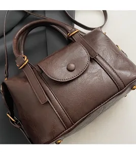 Detail of dark brown embossed leather handbag with golden adjustable buckles and hardware