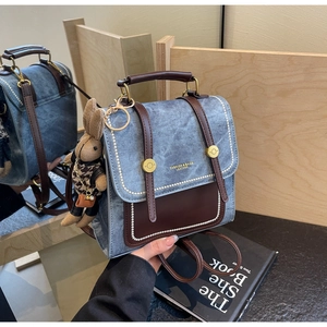 Detail eines Vintage-Jeans-Rucksacks mit brauner Ledertasche und Kaninchen-Anhänger