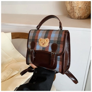 Dettaglio di un mini zaino scozzese vintage con toppa a forma di orsetto e pelle