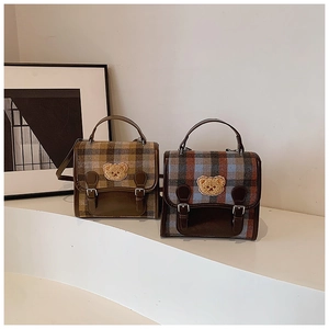 Detailed close-up of British retro plaid fabric textures and bear embroidery on handbags