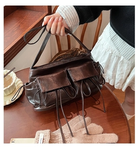 Detail of dark brown vintage shoulder bag featuring glossy texture and drawstring pockets