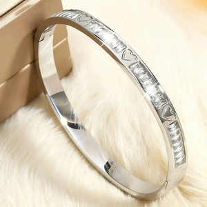 Détail macro du bracelet en acier argenté avec cœurs ajourés et zircons rectangulaires