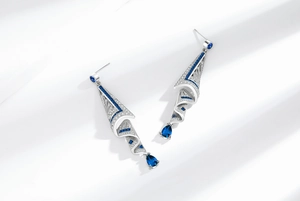 Macro detail of silver drop earrings with blue crystal pear-shaped gems and tassel