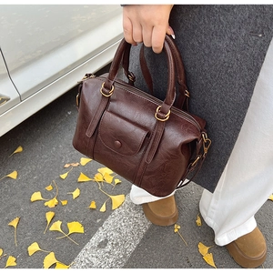 Detail of a dark brown vintage Boston bag featuring a front pocket and bronze hardware
