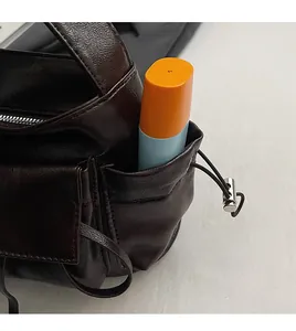 Detail of dark brown leather shoulder bag featuring a side drawstring pocket for storage