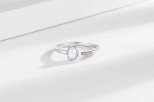 Macro detail of adjustable silver ring with oval white opal and pink zircon accents