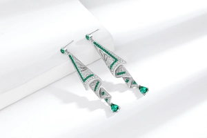 Macro shot of silver drop earrings with emerald green stones and pavé set diamonds