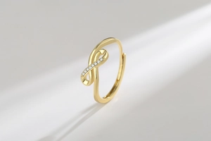 Detailed view of a gold infinity ring featuring elegant crisscross curves and sparkling zircon stones