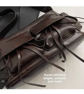 Detail view of smooth dark brown leather shoulder bag with decorative hand-stitched edging
