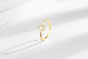 Detailed close-up of golden adjustable ring with oval opal and pink zircon accents