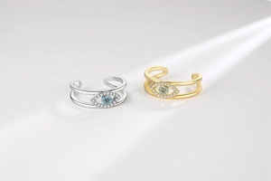 Detailed view of gold and silver evil eye rings with blue stone and pavé accents