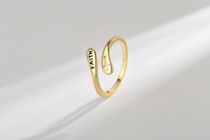 Detail of gold faith cross open ring with engraved text and hollow cross pattern