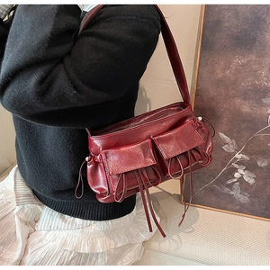 Close-up of retro dark red shoulder bag featuring front flap pockets and slim drawstrings