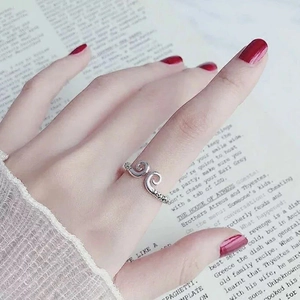 Bague réglable motif nuage Monkey King portée sur la main sur fond de livre vintage ancien