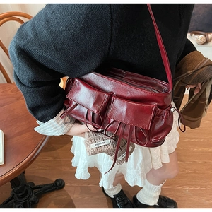 Detailed macro view of dark red glossy leather shoulder bag with vintage buckles and straps