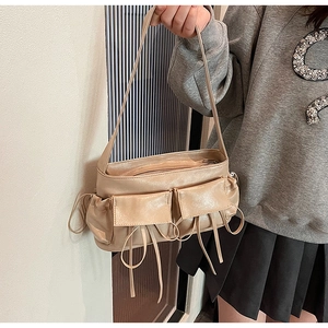 Close-up of beige moon-shaped shoulder bag with decorative drawstring and dual pockets