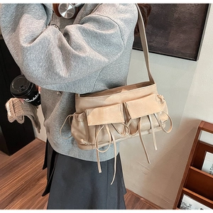 Detail of beige pleated shoulder bag featuring utility pockets and drawstring accents