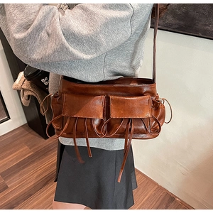 Close-up of vintage brown leather shoulder bag with multi-pocket design and drawstring details