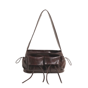 Detail view of dark brown high-gloss faux leather shoulder bag with side drawstring and pockets