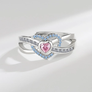 Macro view of heart-shaped pink zircon ring with blue stone halo and silver band