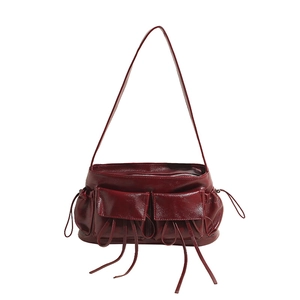 Close-up of wine red glossy leather shoulder bag with double pockets and long tassels
