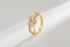 Macro shot of gold ring featuring a pink heart stone and double-row hollow band