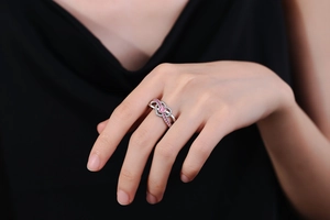 Close-up of heart-shaped pink zircon ring with pavé-set stones on intertwined band