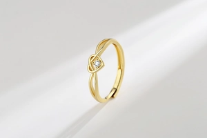 Detail of gold heart knot ring with white gemstone and adjustable open band design