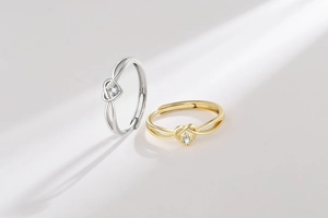Close-up of interlocking heart-shaped rings in gold and silver with sparkling crystal inlay