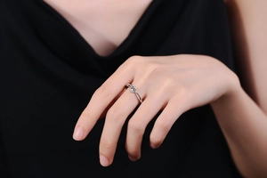 Close-up of minimalist heart knot ring with sparkling zircon on a female hand