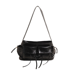 Close-up of black high-gloss PU leather shoulder bag with pockets and drawstring details