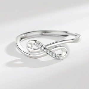 Polished silver infinity ring with sparkling cubic zirconia on a minimalist grey background