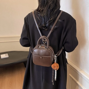 Deep brown mini PU leather backpack with a cute poodle charm shown on model's back