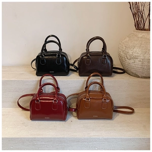 Mini Boston bags in black, brown, burgundy, and tan leather shown on stone steps