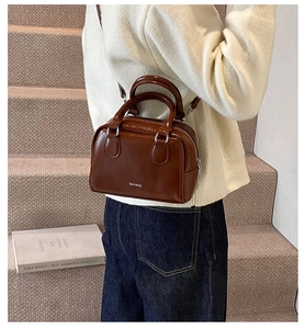 Brown oil wax leather Boston bag shown on a model in a cozy autumn street style setting