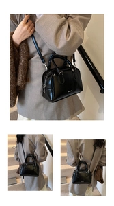Detailed view of black patent leather Boston bag with dual handles and shoulder strap