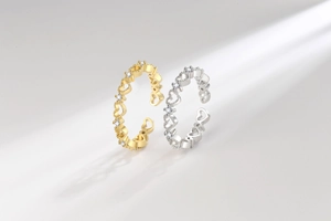 Détail macro de bagues cœur évidé ajustables en or et argent avec pierres de zircon