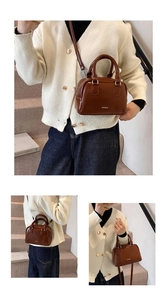 Detail view of a vintage brown leather Boston bag with a logo and detachable strap