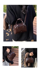 Detail of a brown glossy leather bowling bag featuring double handles and a logo
