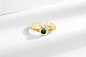Detailed macro view of vintage gold ring with green zircon and intricate hollow carving