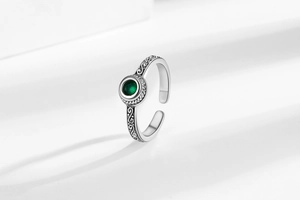 Macro detail of retro silver open ring with green zircon and ornate vintage engravings