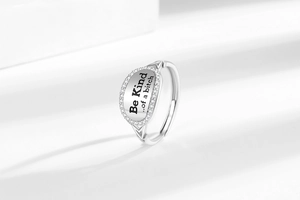 Macro view of adjustable silver ring with Be Kind engraving and pavé zircon border