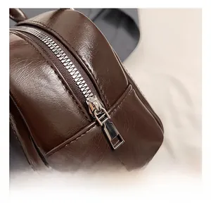 Detailed close-up of dark brown oil-wax leather texture and silver hardware on a Boston bag