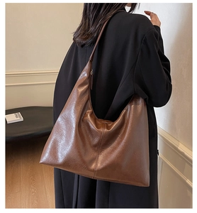 Macro detail of the glossy dark brown leather texture and slouchy design of the tote bag