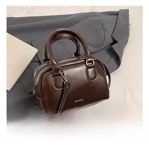 Detail shot of a dark brown oil wax leather Boston bag with silver hardware and logo