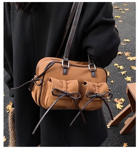 Détail du sac porté épaule caramel avec nœuds sur fond de feuilles de ginkgo en automne
