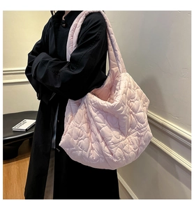 Detail view of large pink puffer tote with heart-shaped quilting and zipper on black coat