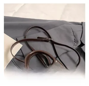 Detail view of smooth dark brown leather bowling bag handle and strap on a stylish blazer